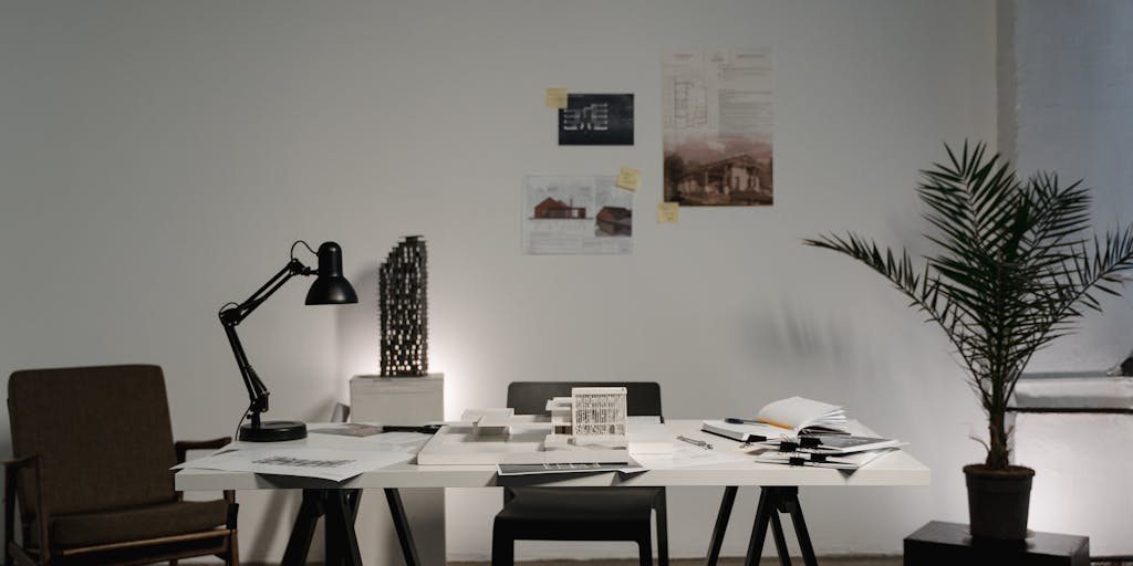 An overhead shot of a desk cluttered with various pricing plans and charts, alongside a small plant growing out of a pot shaped like a robot. This juxtaposition symbolizes growth and innovation in pricing strategies, with the plant representing the potential for business growth through effective pricing.