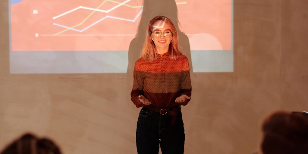A dynamic image of a person pointing at a large screen displaying the Evaboot pricing chart during a presentation. The audience is engaged, with expressions of interest and curiosity, showcasing the importance of understanding pricing in a business context.