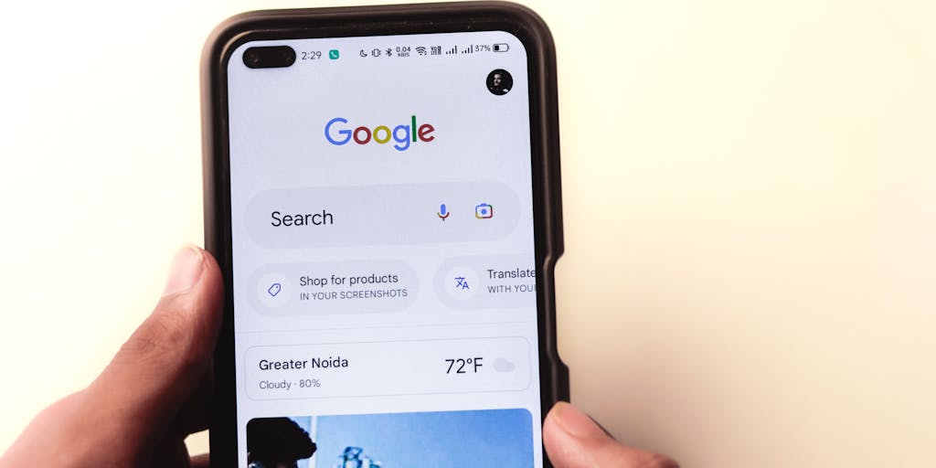 A close-up shot of a hand holding a smartphone displaying the Mailmeteor pricing page, with a blurred background of a cozy home office. The focus is on the screen, showcasing the pricing tiers, while the warm lighting creates an inviting atmosphere.