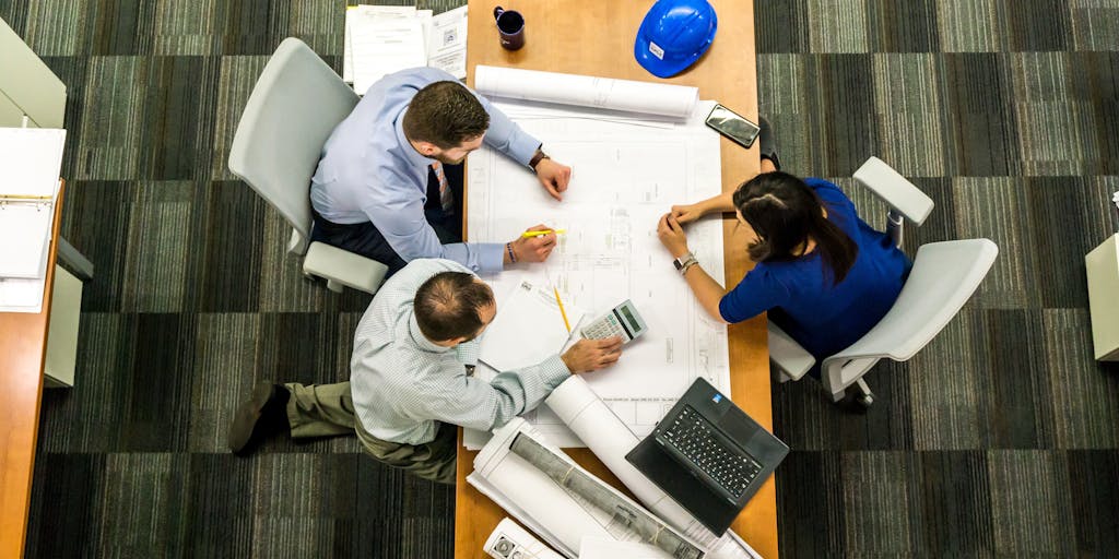 A dynamic shot of a team meeting in a modern conference room, with a large screen displaying the Sales Loft pricing structure. Team members are engaged in discussion, pointing at the screen, showcasing collaboration and decision-making.
