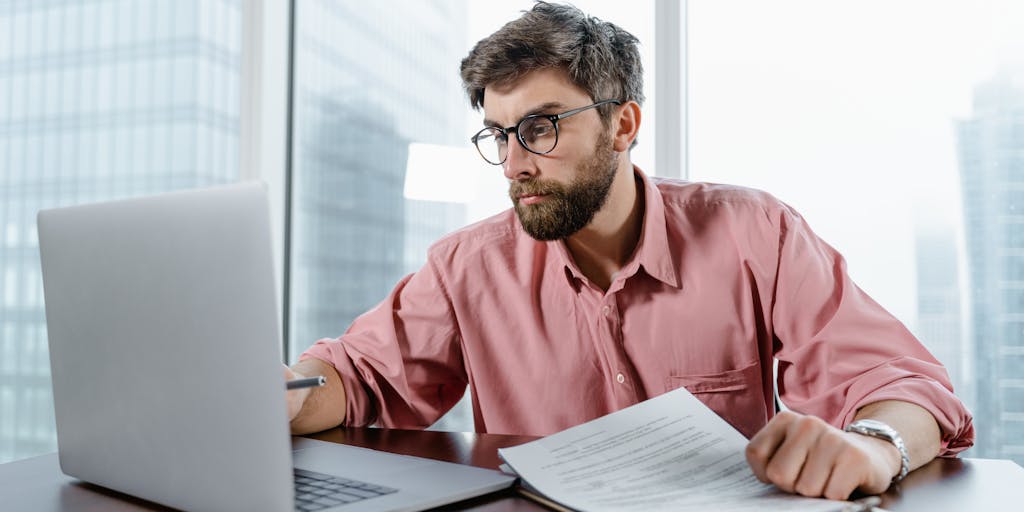 An overhead view of a desk cluttered with various pricing documents, a laptop open with an email draft ready to send, and a cup of coffee. The scene conveys a sense of urgency and productivity, highlighting the concept of quickly emailing pricing details.