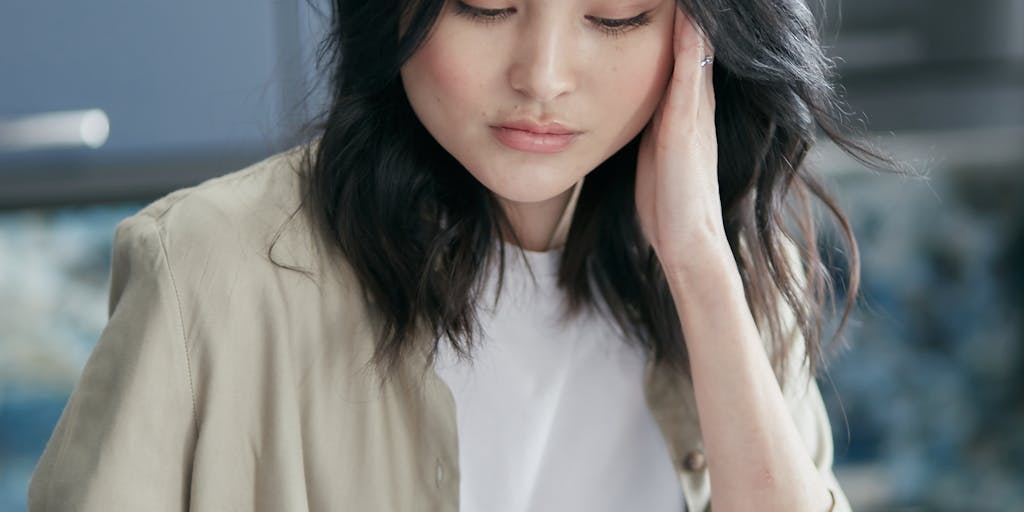 A person sitting at a desk, looking thoughtfully at a laptop displaying the Findymail pricing page, with a notepad and pen in hand. The expression of contemplation suggests the decision-making process involved in choosing a pricing plan.
