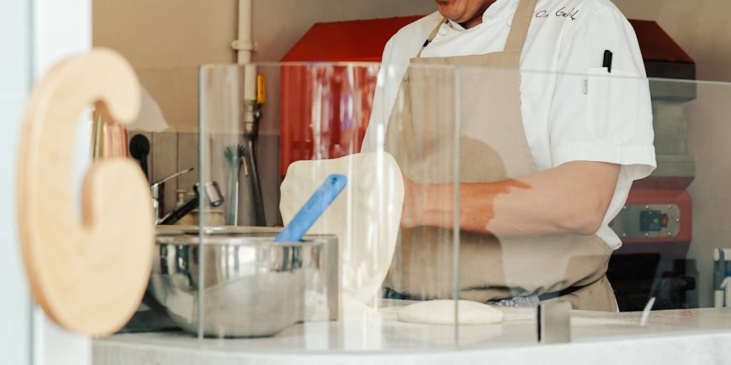 A dynamic shot of a chef in a bustling kitchen, holding a plate of a signature Yamm dish with a price tag hanging from it. The background shows the kitchen in action, highlighting the effort and skill that goes into creating the dishes, while subtly showcasing the pricing.