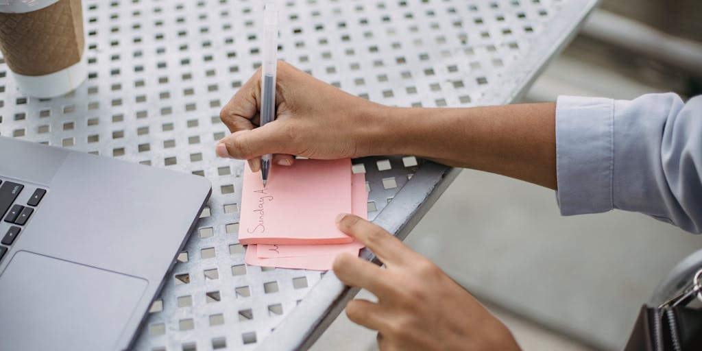 An overhead view of a workspace featuring a laptop open to the Uptics Pricing page, surrounded by colorful sticky notes and a cup of coffee. The vibrant colors of the notes symbolize brainstorming and planning, emphasizing the importance of pricing strategies in business.