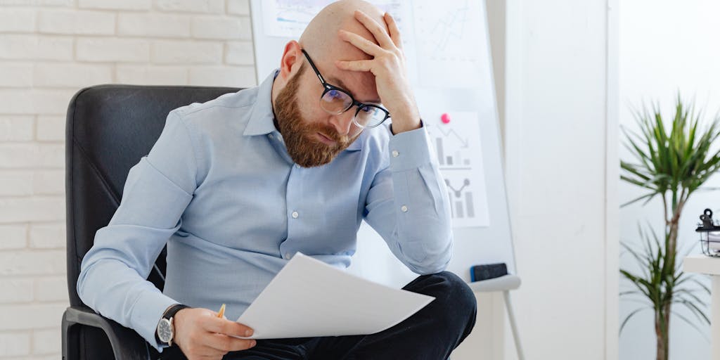 A dynamic image of a person sitting at a desk, looking thoughtfully at a whiteboard filled with Gmelius pricing options and pros and cons. The person is holding a pen, ready to make a decision, capturing the moment of contemplation in a business setting.