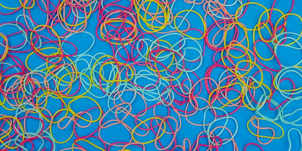 A close-up shot of a flexible rubber band stretched between two fingers, symbolizing the concept of elasticity in pricing. The background features a blurred graph showing fluctuating prices, representing the dynamic nature of email pricing models.