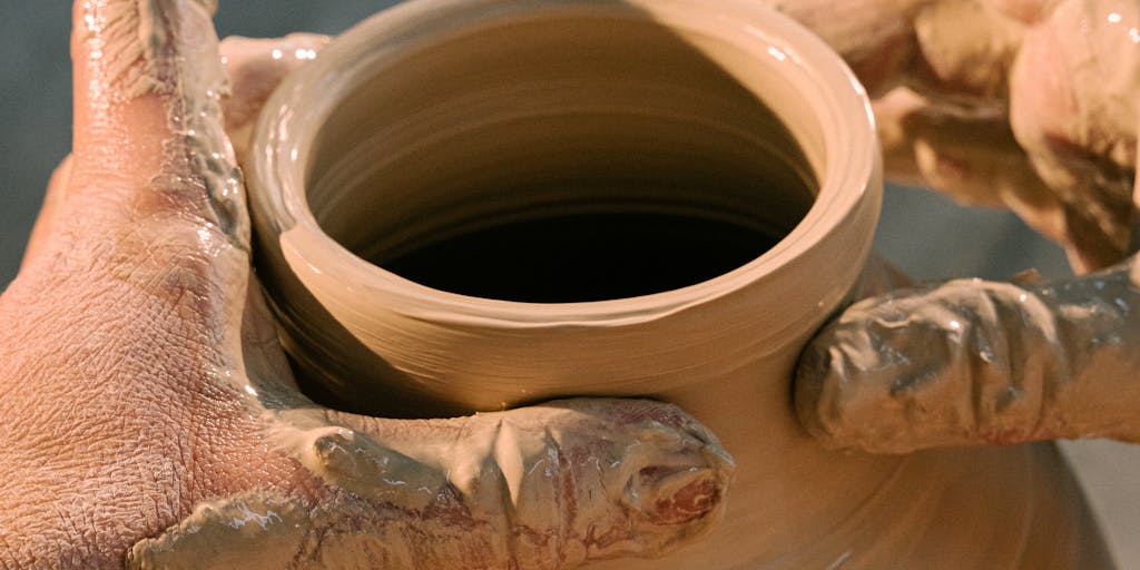 A close-up shot of a hand sculpting a clay model, with various pricing tags made of clay scattered around the workspace. The tags should have different prices written on them, symbolizing the different pricing tiers of Clay.com. The background should be softly blurred to emphasize the clay work.
