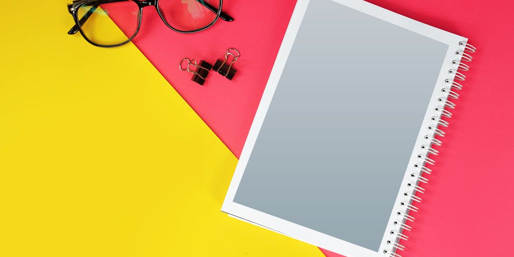 An artistic flat lay of a desk featuring a laptop displaying the Canary Mail pricing page. Surrounding the laptop are various items like a calculator, notepads, and a cup of coffee, all in a bright yellow color scheme. This setup conveys a professional yet creative workspace where pricing decisions are made.