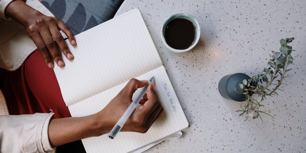 An overhead view of a workspace with a notepad, pen, and a cup of coffee, alongside a smartphone displaying the ZoomInfo app. The notepad has handwritten notes comparing different pricing tiers, showcasing a casual yet professional environment.