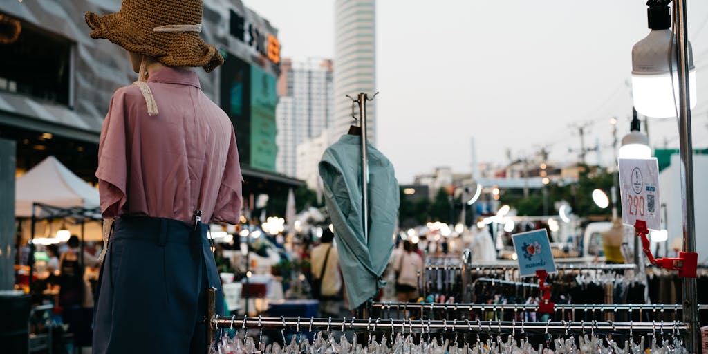 An overhead shot of a busy marketplace where vendors are displaying their products with various price tags. In the foreground, a hand is seen holding two price tags from different vendors, with a visual effect that shows them blending together, representing the idea of merging prices.