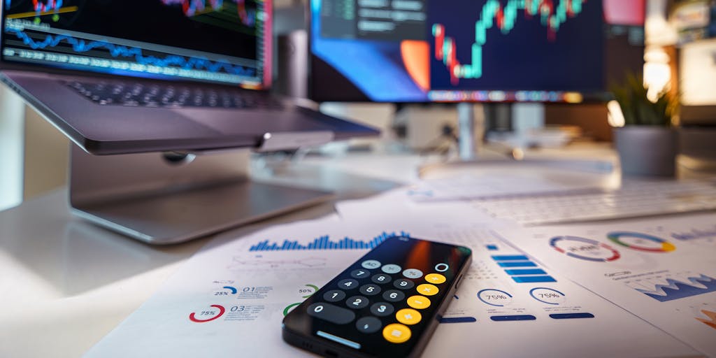 An overhead view of a desk cluttered with notes, a calculator, and a laptop open to the Gmass pricing page. The notes should have scribbled calculations and comparisons, showcasing the thought process behind choosing the right pricing plan.