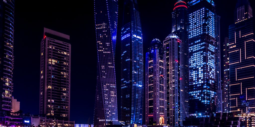 A vibrant, futuristic city skyline at dusk, with neon lights illuminating the buildings. In the foreground, a diverse group of people are gathered around a digital display showcasing the 'Apollo Pricing Unlimited' logo, symbolizing innovation and community engagement in technology.