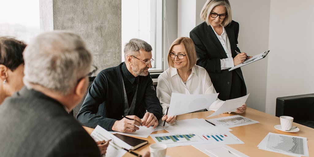 A dynamic image of a diverse group of digital marketers gathered around a table, discussing a Google AdWords campaign. The focus is on their engaged expressions and the digital devices they are using, highlighting collaboration and innovation.