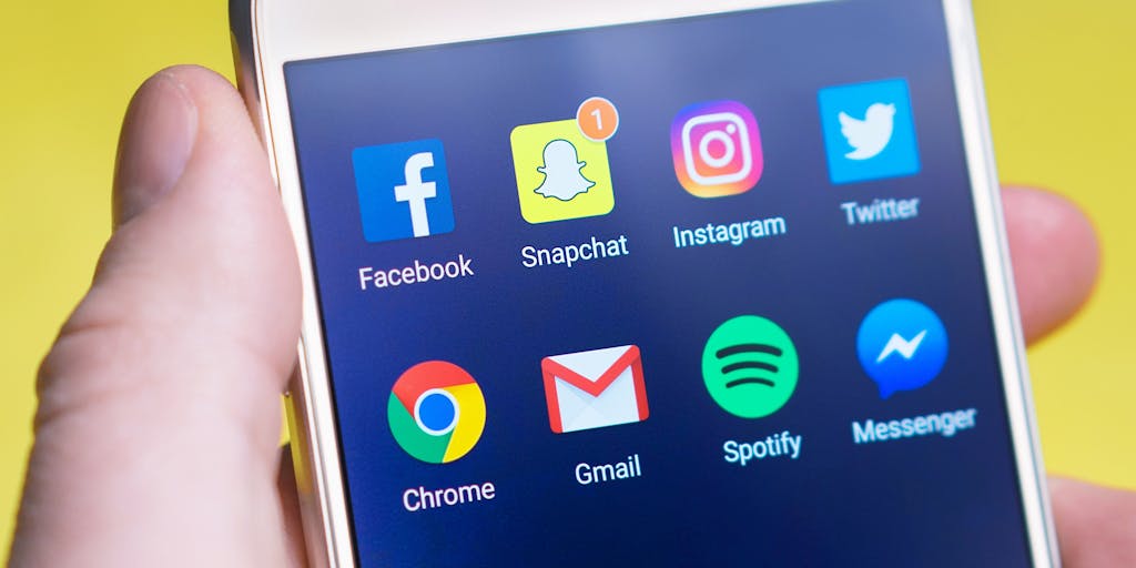 A close-up shot of a smartphone displaying a Snapchat ad campaign in action, with engaging filters and stickers. The phone is held by a diverse group of friends laughing and interacting with the ad, showcasing the fun and engaging nature of Snapchat marketing.