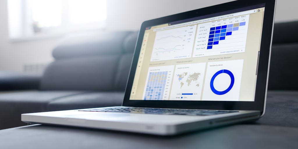 A close-up shot of a laptop screen displaying a Facebook Ads Manager dashboard, with graphs and metrics showing successful ad performance. In the background, a coffee cup and notepad with marketing notes add a personal touch.