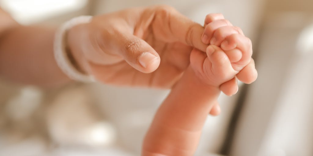A close-up shot of a child's hand holding a parent's hand, with a blurred background of bills and financial documents. This image captures the emotional connection between parent and child while subtly hinting at the financial responsibilities involved in child support.