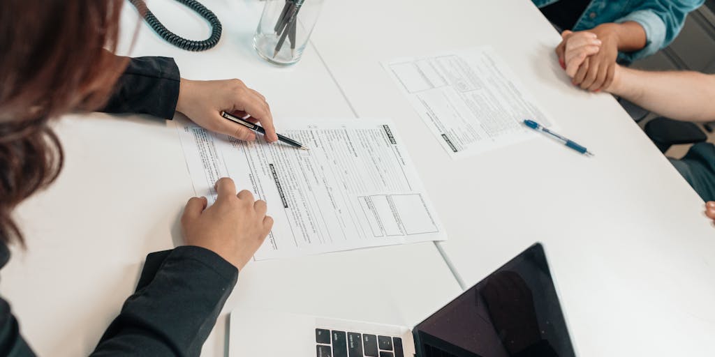 A close-up shot of a mother sitting at a kitchen table with a laptop open, looking determined while filling out child support forms. The background shows a child’s drawing on the fridge, symbolizing the importance of support for the child’s future.