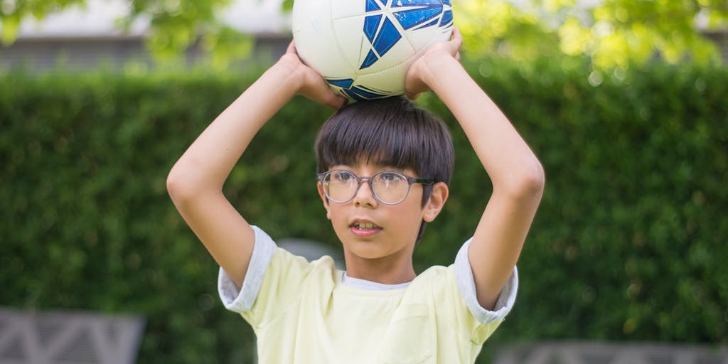 A close-up shot of a child's hands holding a variety of items: a school book, a soccer ball, and a healthy snack. This image symbolizes the diverse aspects of a child's life that child support is intended to cover, from education to extracurricular activities and nutrition.