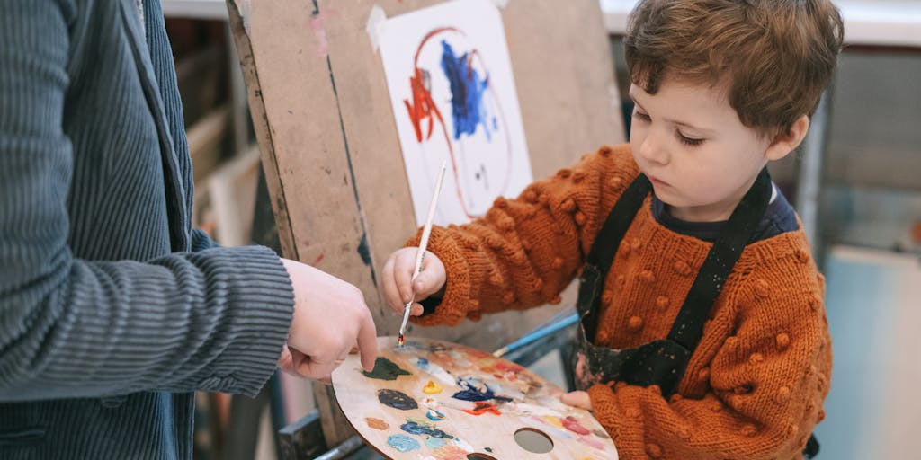 A close-up shot of hands holding a child’s drawing that depicts a family, with a visible disability symbol in the corner. The hands belong to a parent who looks contemplative, suggesting the emotional struggle of navigating child support while managing a disability. The background is softly blurred to keep the focus on the drawing.
