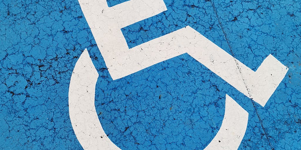 A conceptual photo of a road sign that reads 'Child Support Ahead' with a detour sign indicating 'Disability'. The setting is a winding road, symbolizing the complex journey of navigating child support laws related to disability. The sky is overcast, adding a sense of uncertainty to the journey.