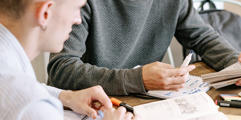 A family sitting together at a dining table, discussing college plans with a laptop open showing a college website, while a notepad with child support calculations is visible, illustrating the planning and discussions around education funding.