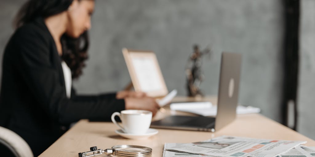 An image of a person sitting at a desk with a laptop open, looking thoughtfully at a checklist titled 'Steps to Terminate Child Support'. The desk is cluttered with legal papers, a coffee cup, and a family portrait, conveying the seriousness of the process.