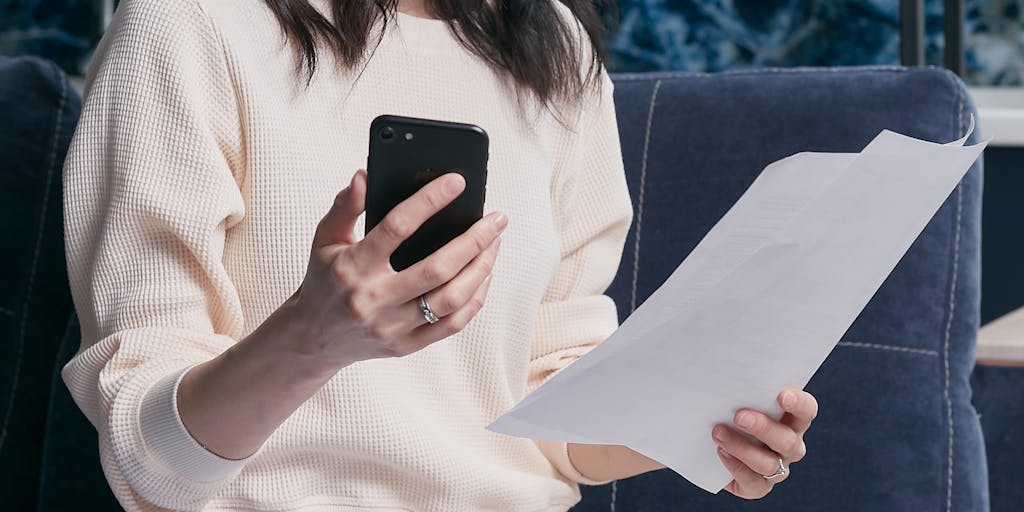 A close-up shot of a hand holding a calculator with a notepad beside it, where the notepad has 'Child Support' written at the top. The background features a family photo, symbolizing the connection between finances and family support.