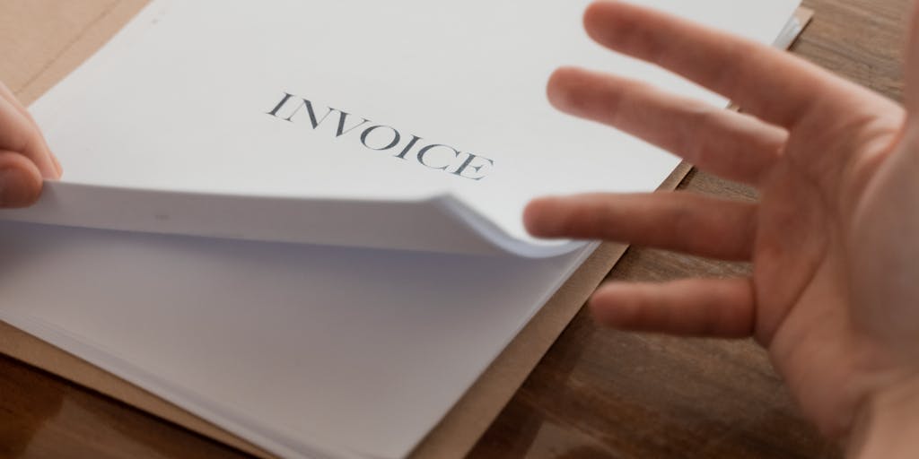 A close-up shot of a hand holding a child support check with a blurred background of tax documents. The focus on the check emphasizes the financial aspect, while the blurred documents represent the complexities of tax implications.