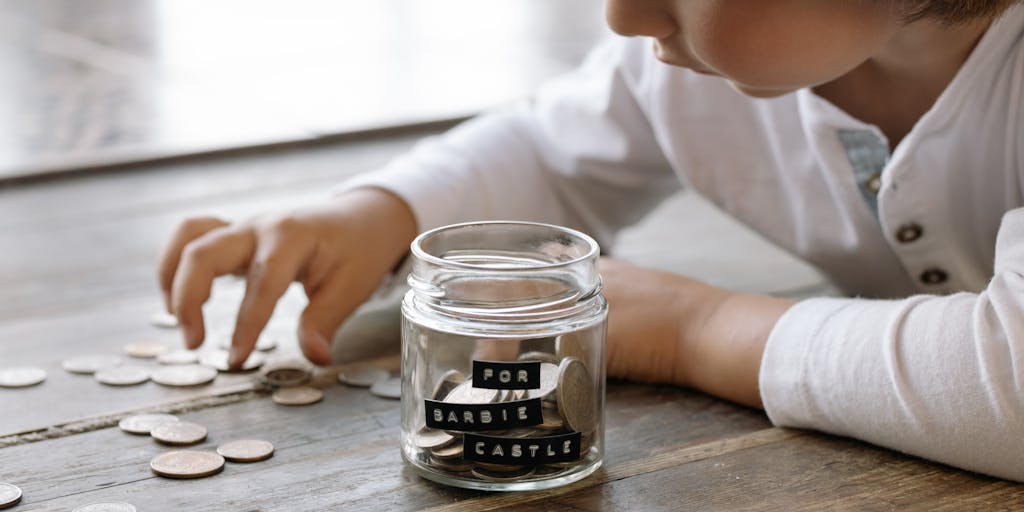 A close-up shot of a hand holding a stack of coins with a blurred background of a parent and child playing together. This image symbolizes the financial aspect of child support while highlighting the emotional connection between parent and child.
