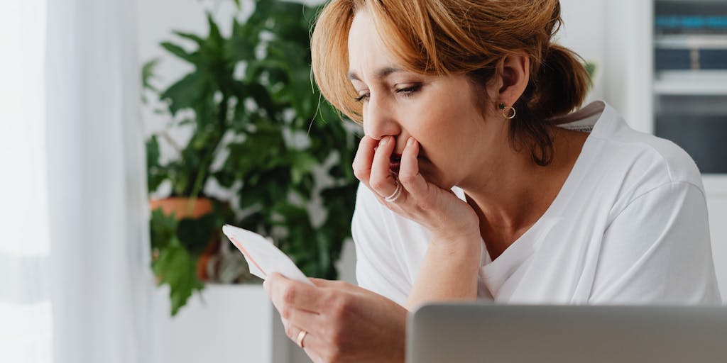 A split image showing a mother at home with her child on one side, looking worried while reviewing bills, and on the other side, a close-up of a child’s drawing depicting a happy family. This juxtaposition highlights the emotional impact of financial stress on single parents.