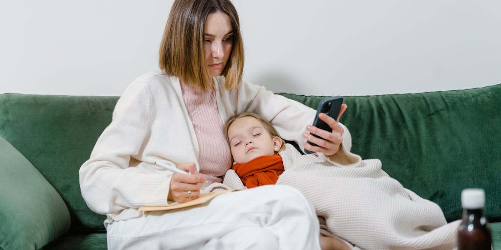 An image of a mother sitting at a kitchen table with a laptop open, looking at child support resources online, surrounded by her child’s toys. This scene captures the search for information and support while managing parenting responsibilities.
