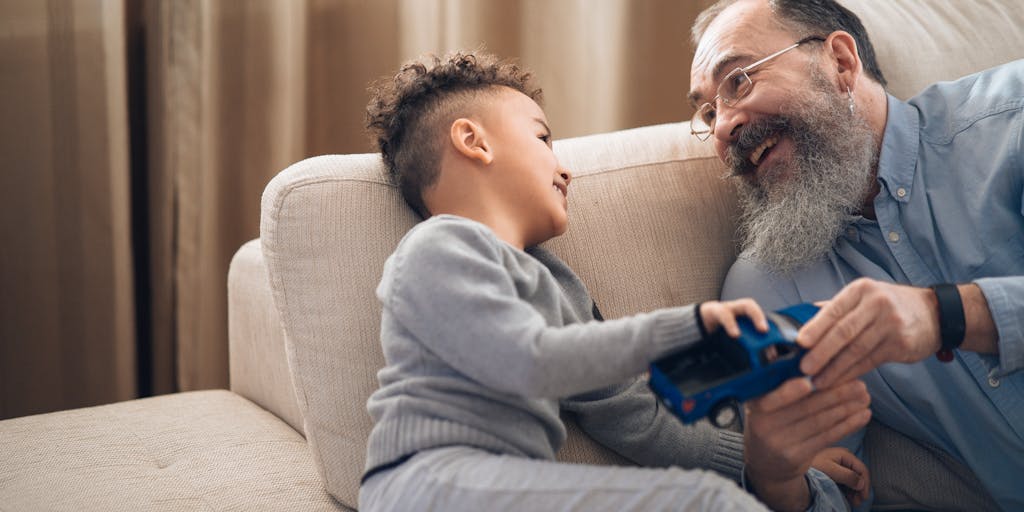 A heartwarming scene of a grandparent sitting at a kitchen table with a child, both looking at a stack of bills and a calculator. The grandparent is explaining the importance of budgeting for child support, with a warm, inviting kitchen background that conveys family love and responsibility.