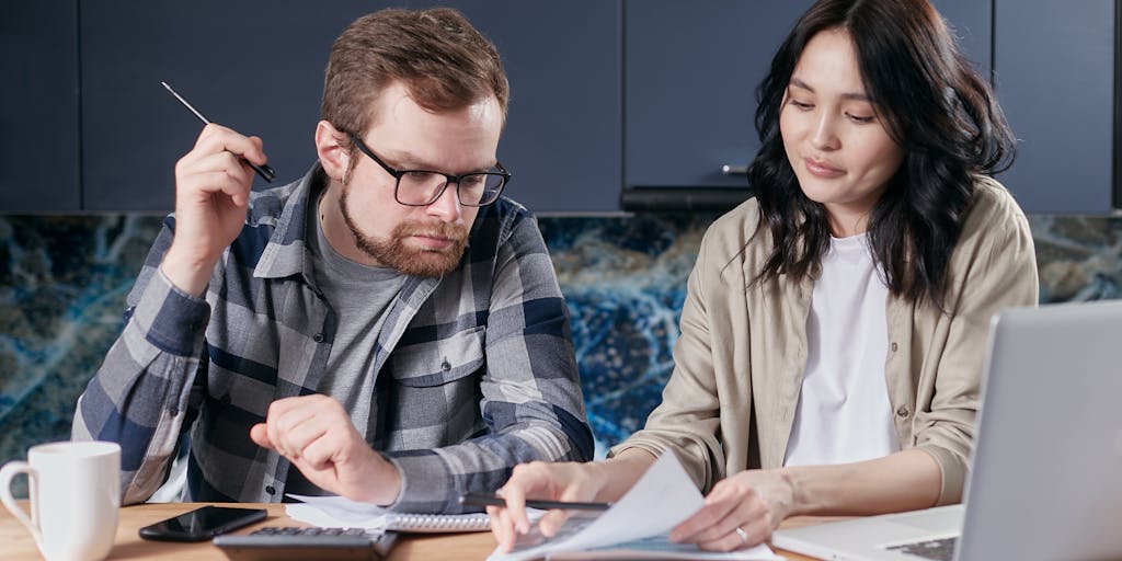A family sitting around a table with documents spread out, including a VA disability letter and child support forms. The atmosphere is collaborative, showing the family discussing finances together, highlighting the importance of communication in financial matters.