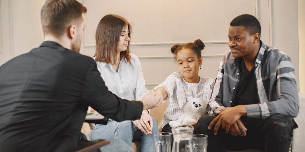 A family meeting scene where parents are discussing child support arrangements with a mediator. The setting should be warm and inviting, showing cooperation and understanding, emphasizing the importance of communication in the process.