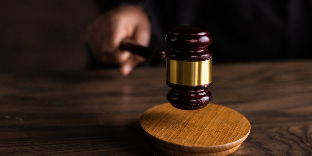 A close-up shot of a gavel striking a sound block, symbolizing the legal process. In the background, blurred images of child support documents can be seen, representing the complexity of child support arrears. The focus on the gavel emphasizes the judicial aspect of dismissing arrears.