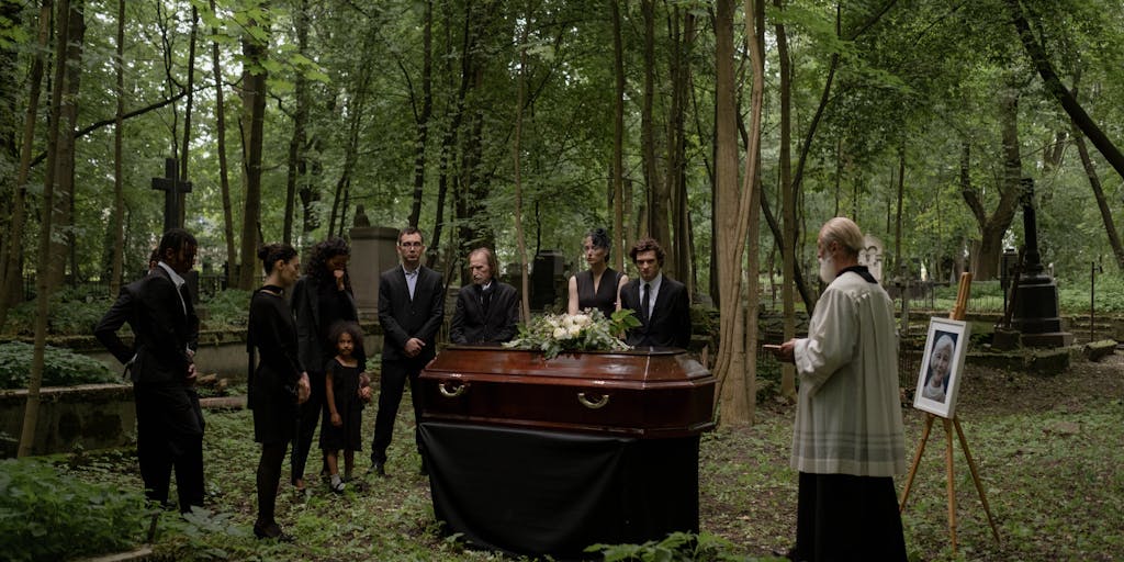 A somber yet hopeful image of a family gathered around a table, looking through old photographs of a loved one who has passed away. The table is adorned with a candle and a framed picture of the deceased, symbolizing the legacy left behind. The atmosphere conveys a sense of reflection on the past and the financial responsibilities that continue even after death.