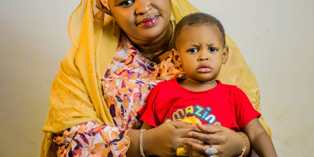 A close-up shot of a mother and child holding hands, with a blurred background of a courtroom. This image captures the bond between them while subtly hinting at the legal complexities of child support.