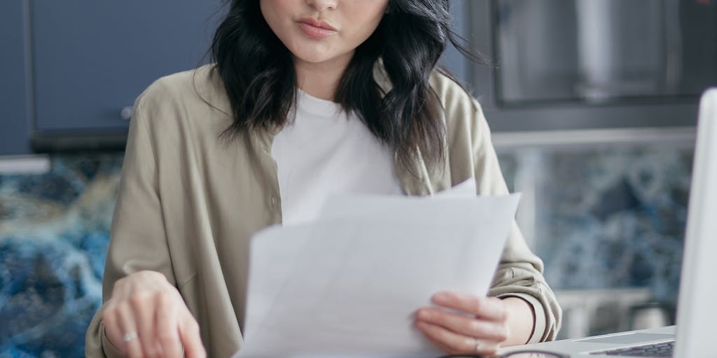 A split image showing a mother sitting at a kitchen table with bills and a calculator, looking stressed, while on the other side, a father in a prison cell looking at a photo of his child. This juxtaposition highlights the emotional and financial strain of child support when a parent is incarcerated.