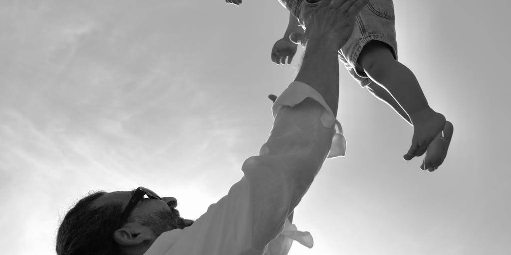 A split image showing two scenarios: on one side, a parent happily playing with their child, and on the other side, a court building with a 'Warrant Issued' sign. This juxtaposition highlights the emotional impact of child support issues on family life.