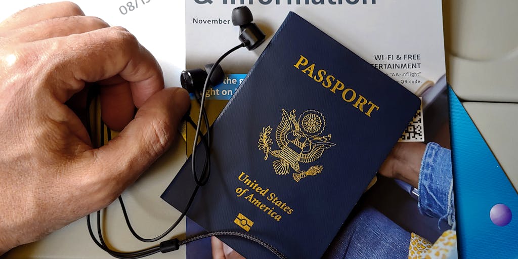 A creative flat lay of a passport, child support documents, and travel essentials like a suitcase and a map, arranged on a wooden table. The contrasting items symbolize the tension between the desire to travel and the responsibilities of parenthood.