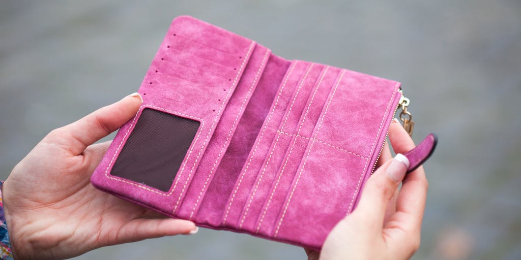 A conceptual photo of a large, empty wallet on a table, with a small child's toy next to it. The wallet has a label that reads 'Child Support' and a shadow of Donald Trump's profile is cast over the scene, representing the financial burden of child support.