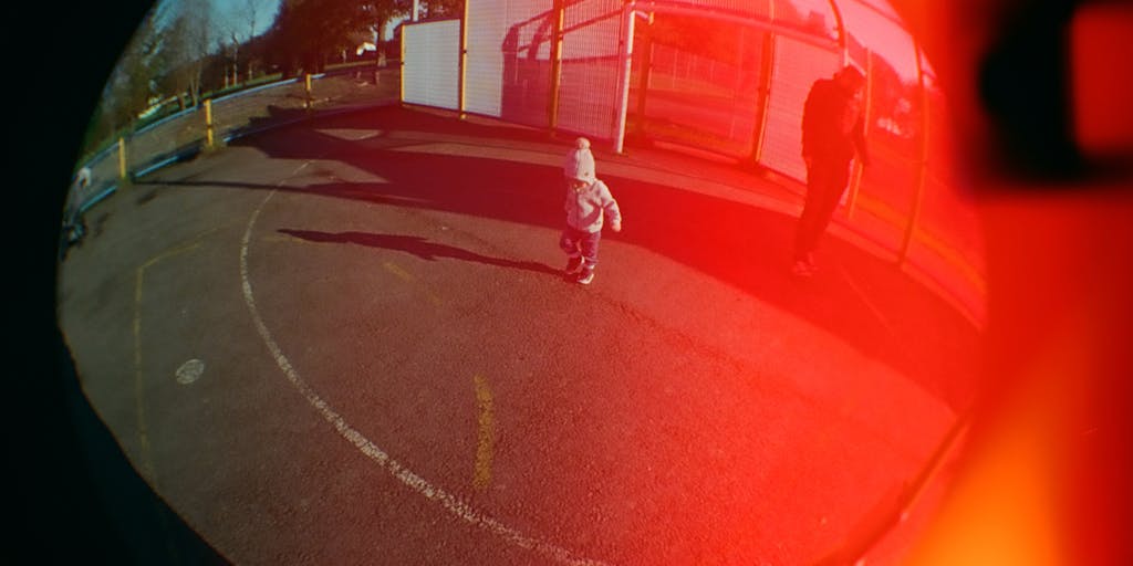 A split image showing two contrasting scenes: on one side, a parent joyfully playing with their child in a park, and on the other side, the same parent sitting alone in a dimly lit room, surrounded by unpaid bills and a worried expression. This visual juxtaposition highlights the emotional impact of not paying child support.