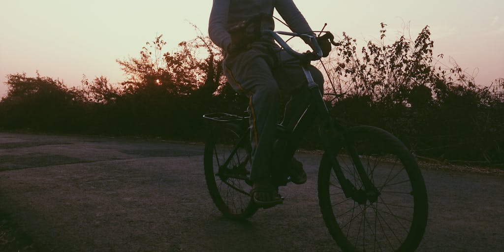 A symbolic photo of a child riding a bicycle down a path, with a sunset in the background. The bike represents freedom and growing up, while the fading light signifies the end of a chapter in child support.