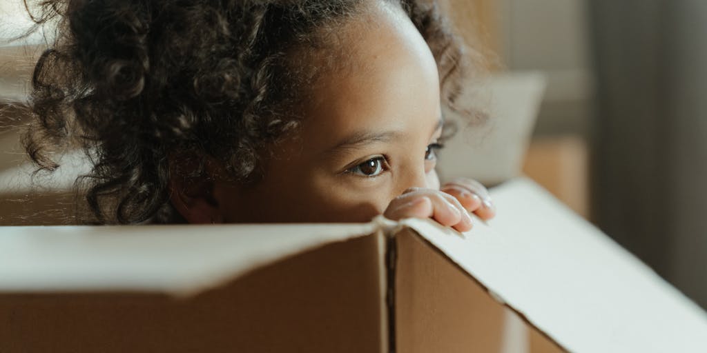 A split image showing two homes, one on each side, with a child happily transitioning between them. The left side features a cozy living room with toys scattered around, while the right side shows a similar setup in a different style. The child is depicted in the center, symbolizing the balance of joint custody.