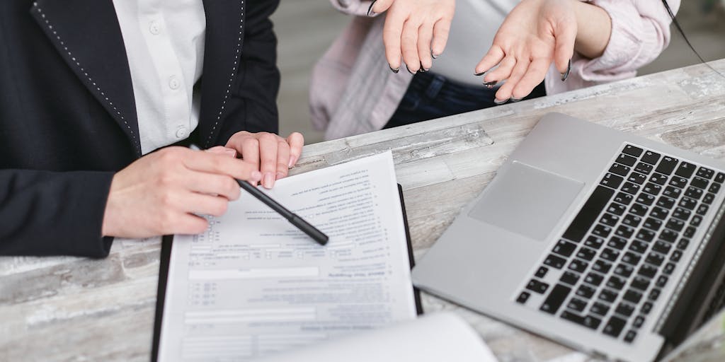 An image of a person sitting at a desk with a laptop open, looking contemplative while reviewing child support laws. The desk is cluttered with papers, a family photo, and a notepad with handwritten notes, illustrating the emotional and logistical aspects of the cancellation process.