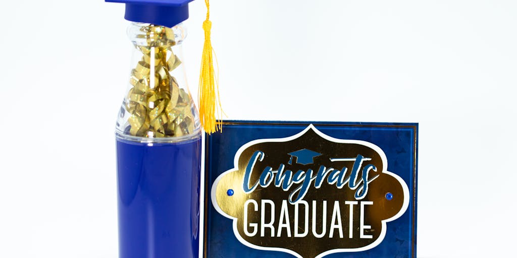 A conceptual photo of a graduation cap and a baby bottle placed side by side on a table. This juxtaposition represents the end of child support as the child grows up and graduates into adulthood, symbolizing achievement and independence.