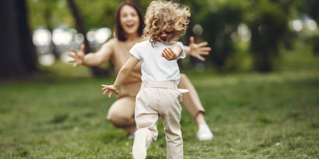 A joyful reunion scene in a park where a parent and child embrace, symbolizing the relief and happiness that comes with the resolution of child support arrears. The background features vibrant greenery and a sunny sky, emphasizing a fresh start.