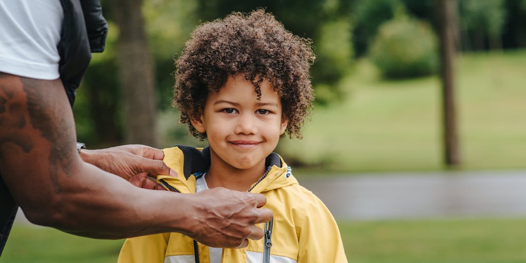 A split image showing a child playing in a park on one side and a father looking at the same park from a distance in another country, symbolizing the emotional distance and the complexities of international child support.